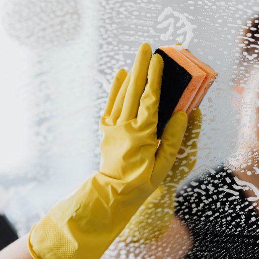 Hand wiping a glass surface with sponge
