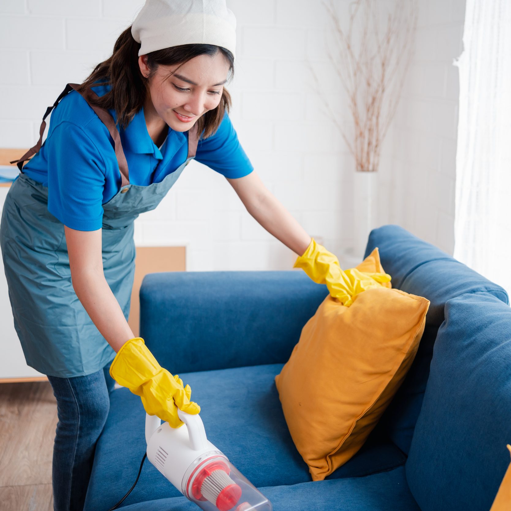 Woman cleaning an upholstery using a vacuum