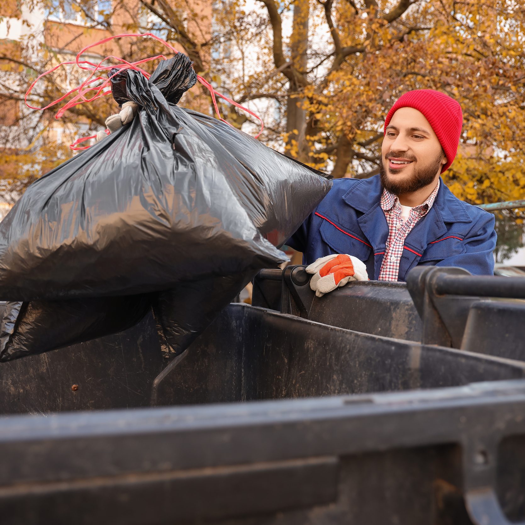 Man putting a bag of trash in a bin